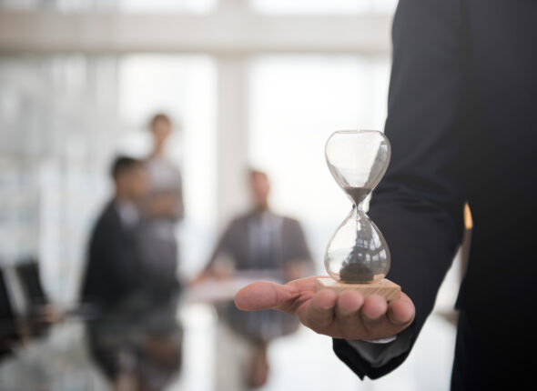 Businessman holding an hour glass, signifies the importance of being on time