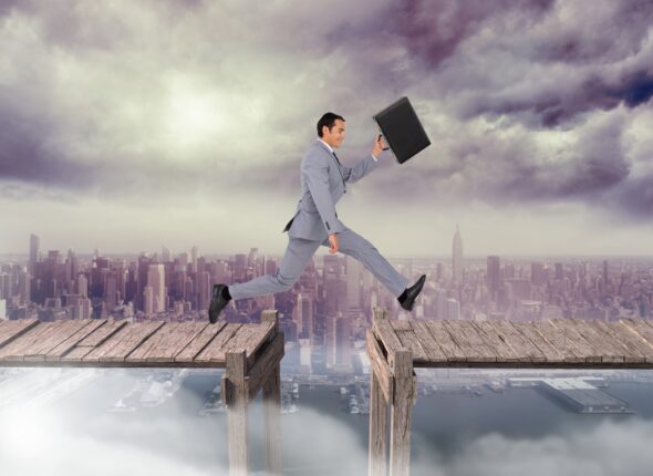 Businessman with briefcase jumping on boardwalk against cityscape in background